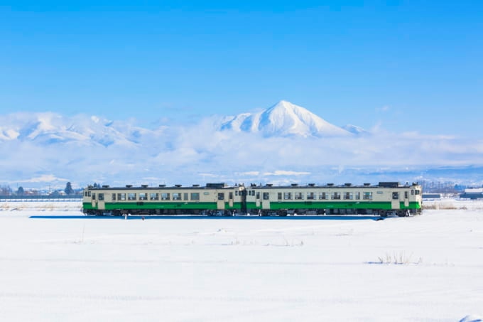磐梯山と雪原を走るJR只見線（福島県会津美里町）