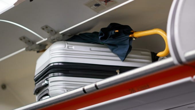 機内のスーツケースと傘
