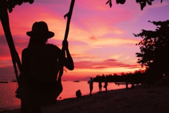 サンセットのビーチを眺める女の人