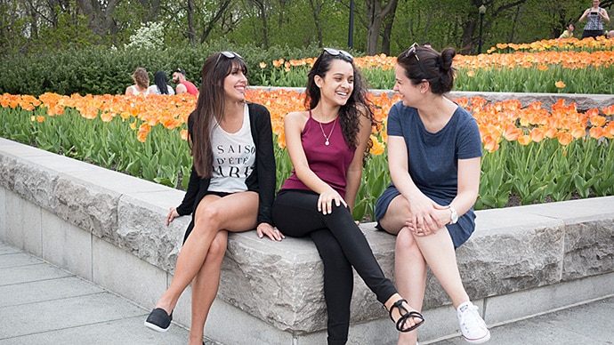 EC Montreal校の3人の生徒が花壇に座って話している様子