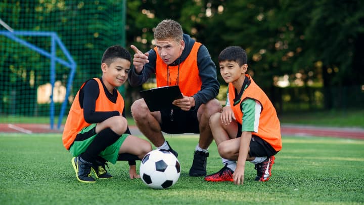 サッカーコーチから指導を受ける子供の写真